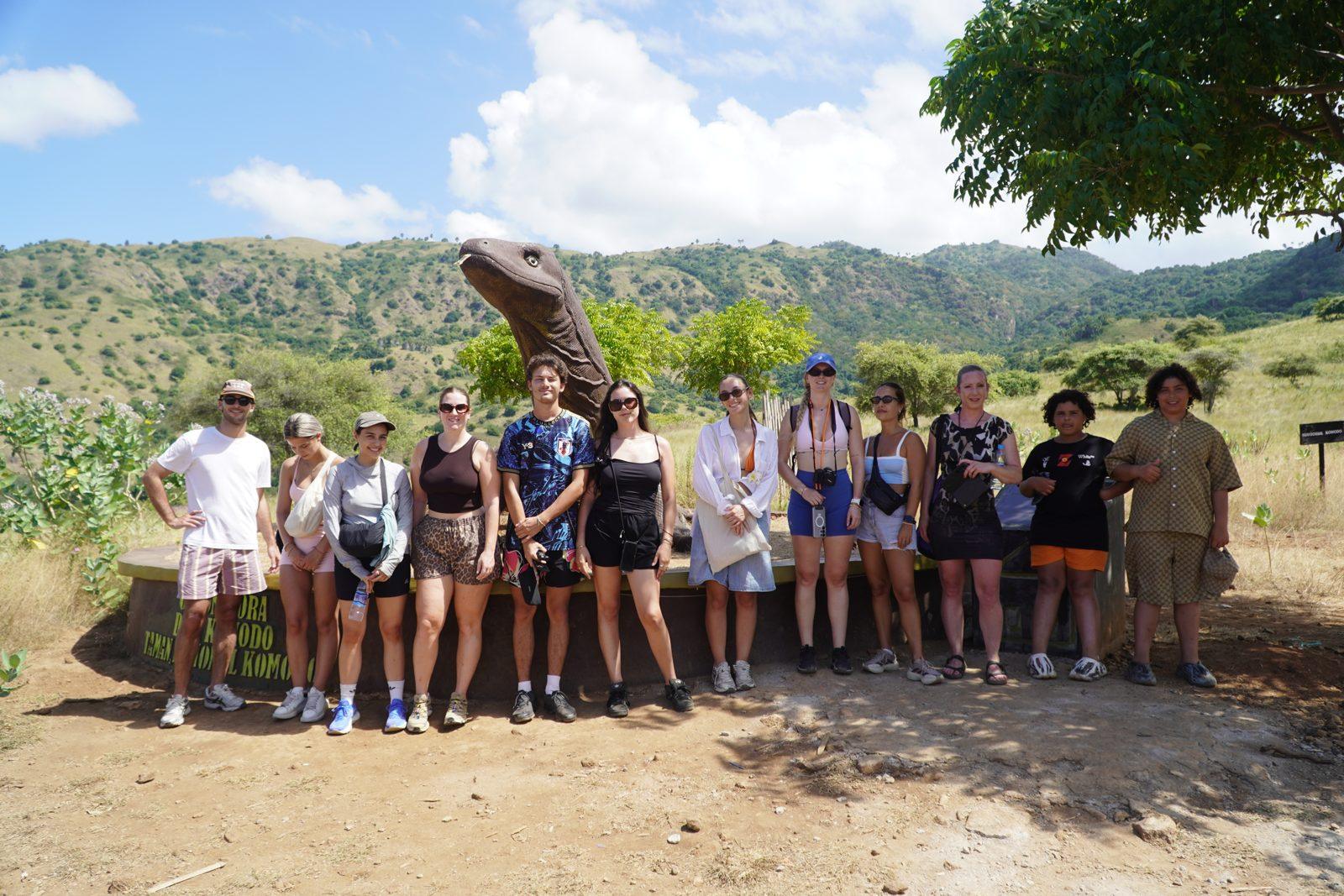 Komodo – group posing on savanna with dragon (Real photo from a KEXI trip)