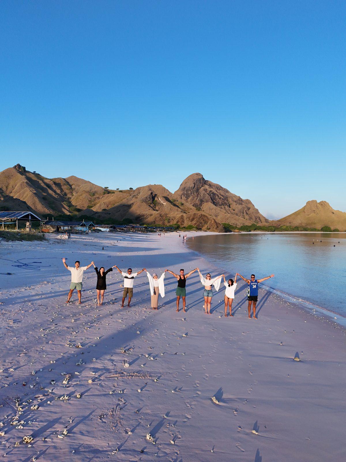 Pink Beach – Group in line on pink sand, hills behind (Real photo from a KEXI trip)