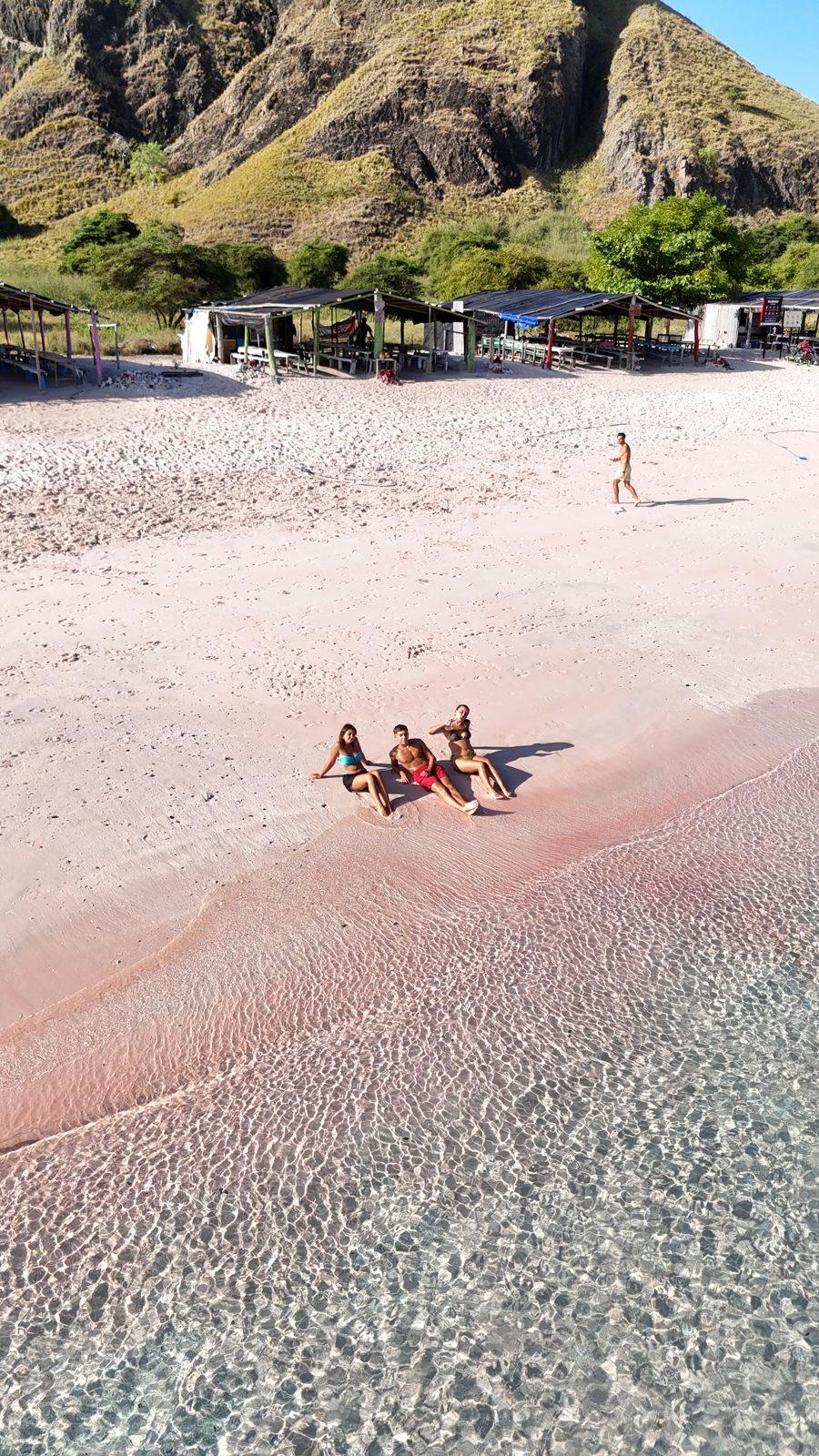 Pink Beach – group lying on pink sand, hill left (Real photo from a KEXI trip)
